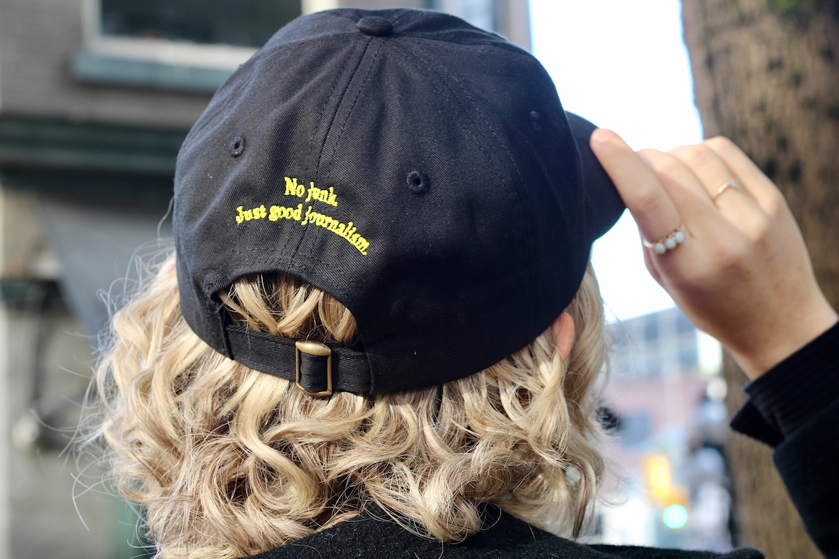 The back of a black baseball cap reads &lsquo;No junk. Just good journalism.&rsquo;