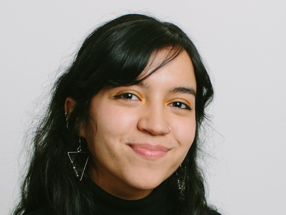 A woman of medium skin tone and curly dark hair, Tyee writer Sarah Krichel, smiles at the camera.