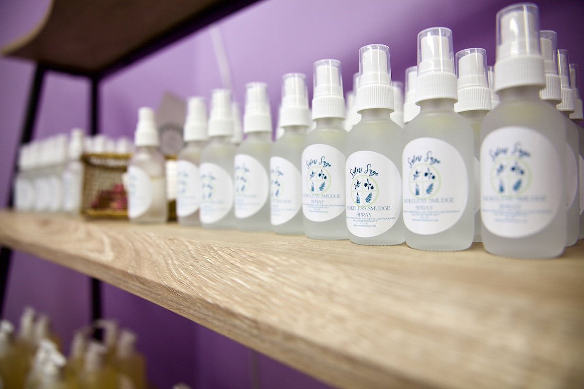 A wooden shelf is stocked with small opaque spray bottles with white labels.