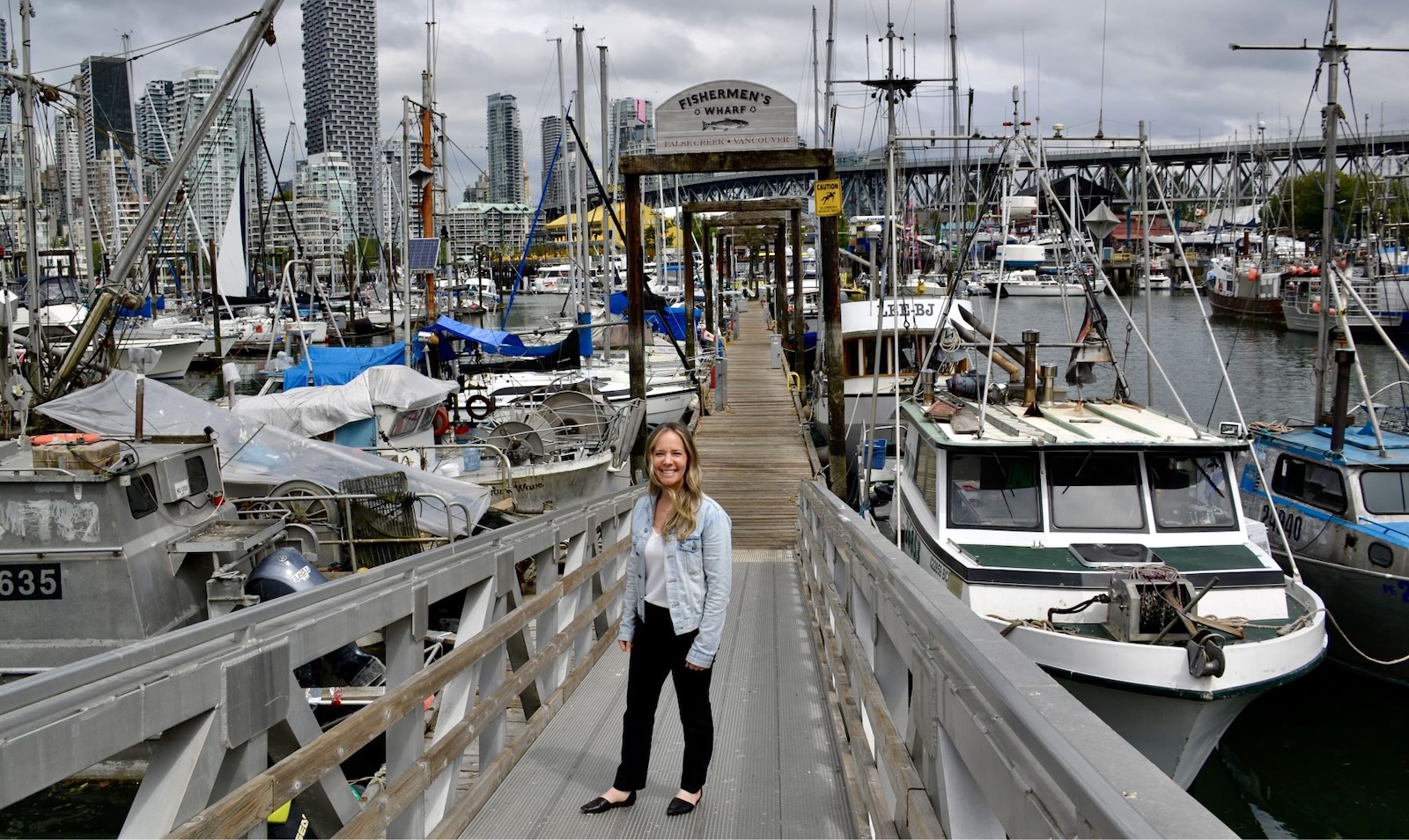 A woman with light skin and long blond hair stands on a gangway surrounded by boats at the Fishermen’s Wharf in Vancouver’s False Creek.