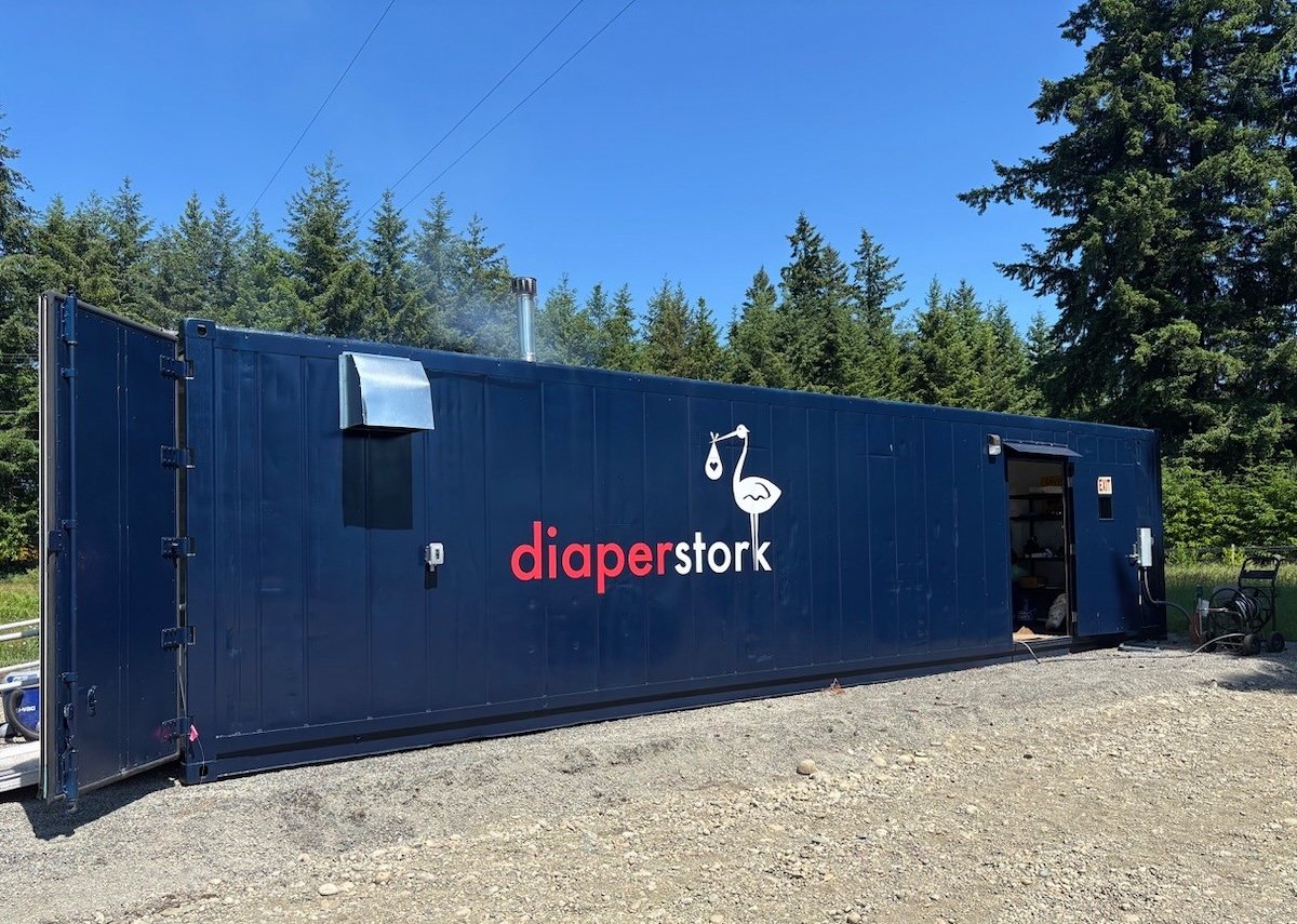 A dark blue shipping container emblazoned with the words ‘diaper stork’ in white and red.