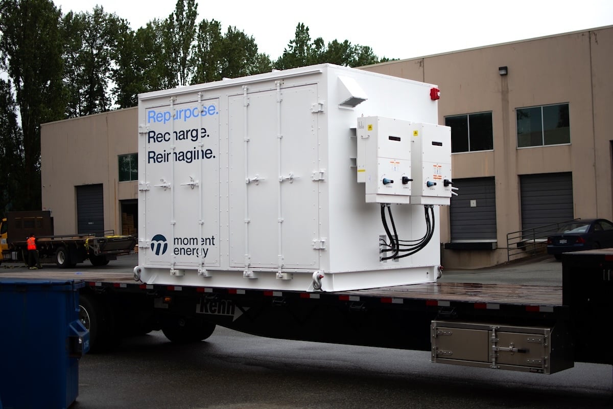 A white shed-looking object sits in an office park. It has the words ‘repurpose, recharge, reimagine’ written on the side.