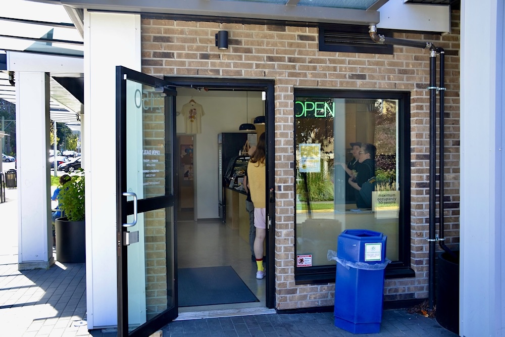 A door leading into the FabLab, one of three parts within MakeSpace North Park. There&rsquo;s an Indigenous mural on a brick wall outside the door. 