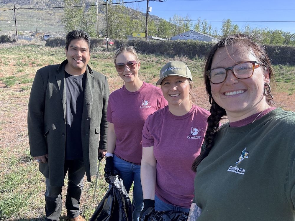 Joshua Gottfriedsen stands on the far left wearing a black jacket. He is smiling beside three women dressed in pink and green shirts. He&rsquo;s attending Tk̓eml&uacute;ps te Secw&eacute;pemc&rsquo;s annual community cleanup. 